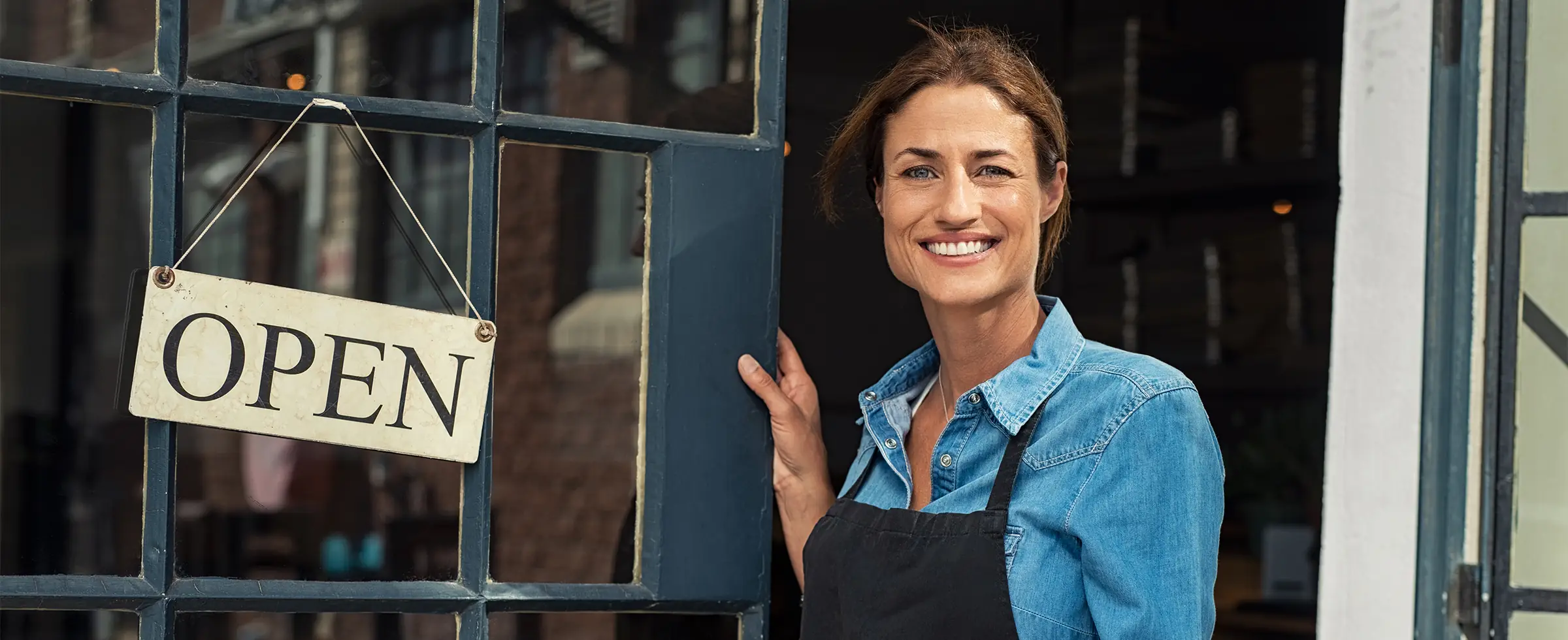happy mature business owner standing in the doorway
