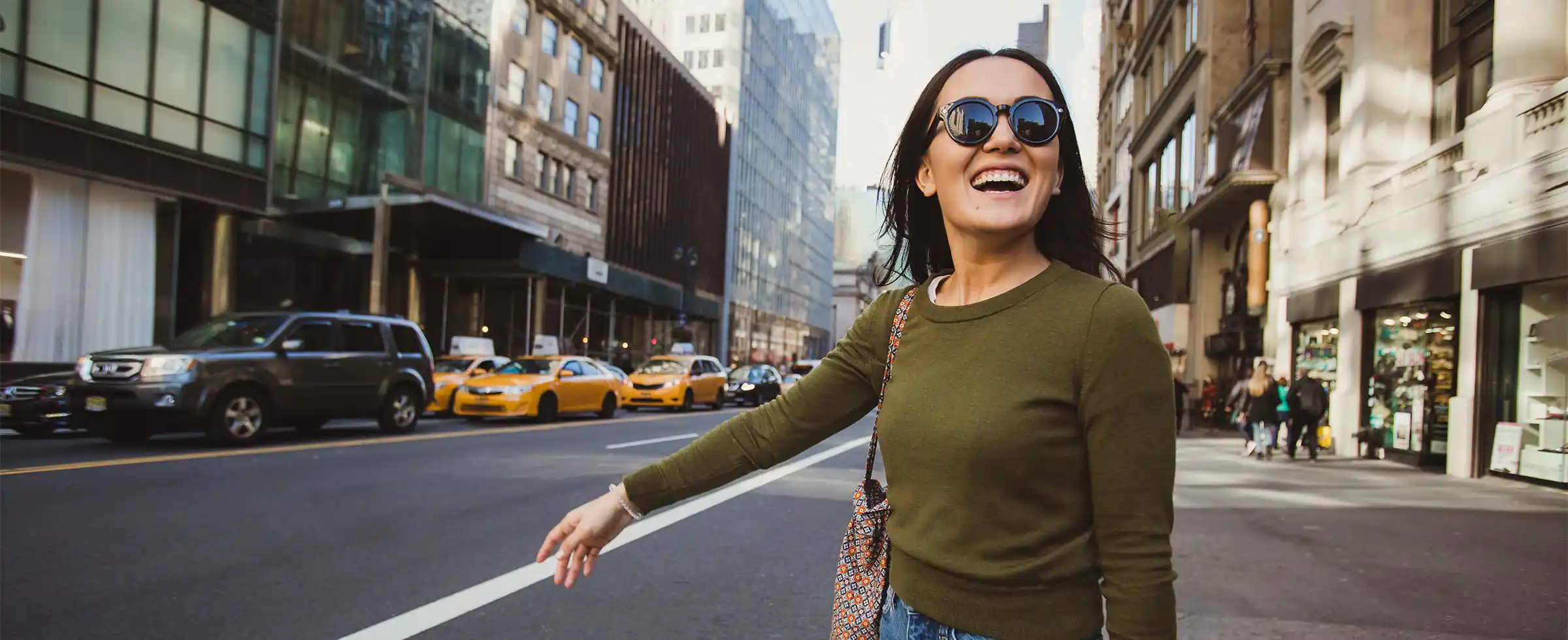 Joyful woman wearing sunglasses while shopping downtown