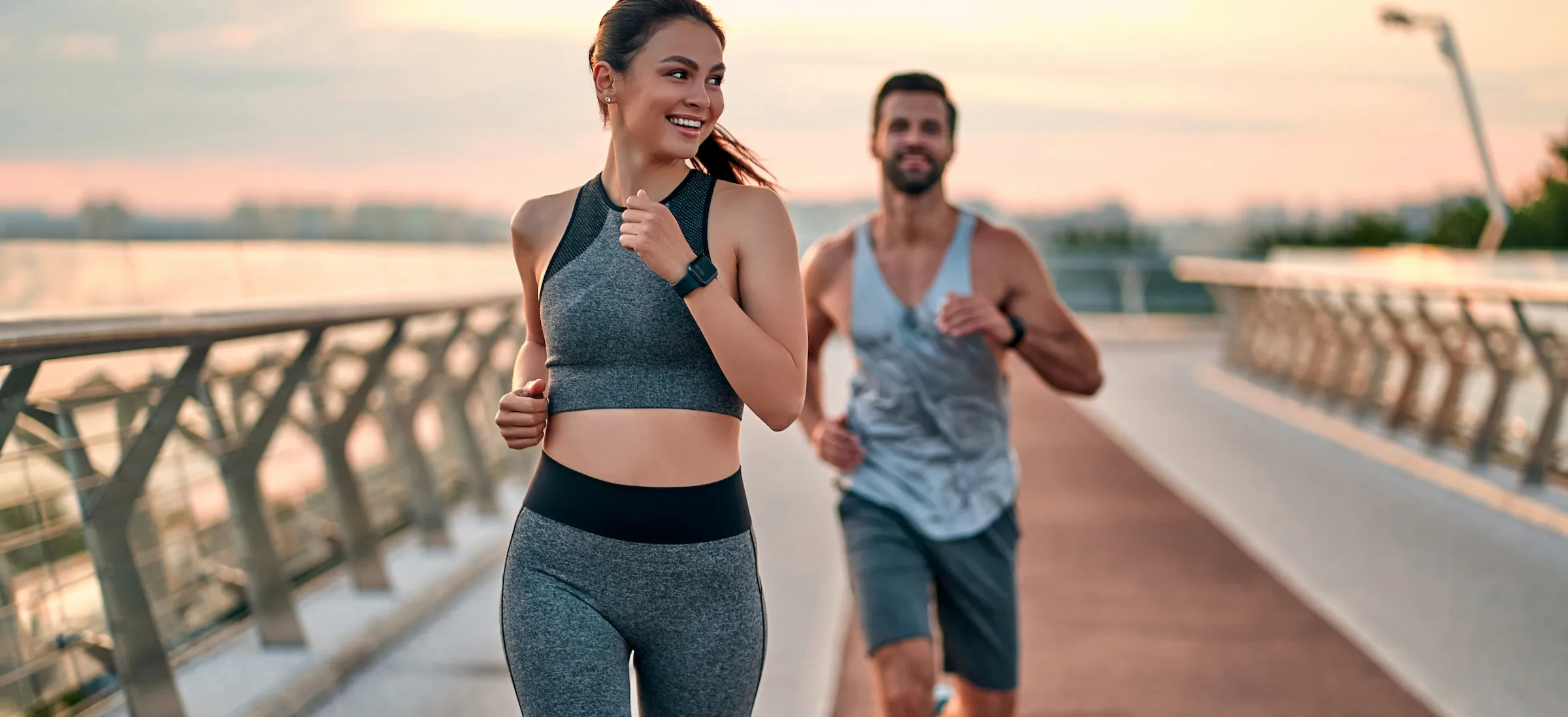 happy healthy couple running together outside on a bridge